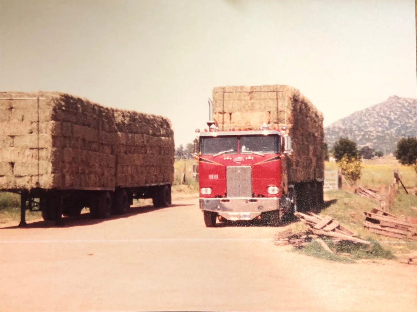 Old vintage hay delivery truck loaded with neatly stacked hay bales.